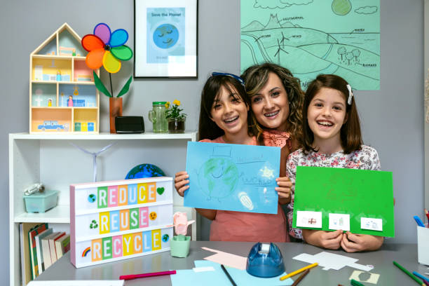 istock Teacher in classroom looking at camera next to students showing colorful ecological drawings 1856784902