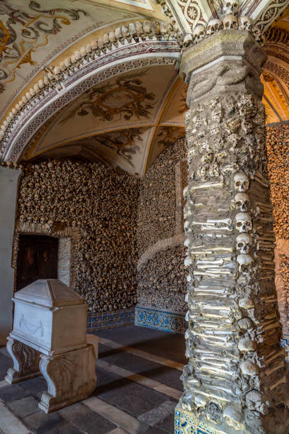 istock Covered column decorated with human bones and skulls, vaulted ceiling with religious allegorical paintings and a marble tomb of the Chapel of Bones. Evora, Portugal. 1856807016