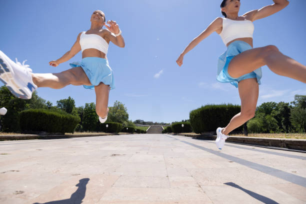 Two young athlete women doing some syncro exercises in the park on full sunny days.