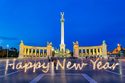 'Happy New Year' light trail sparkler inscription text effect at night at Heroes' Square (Hősök tere) one of the major squares in Budapest Hungary, noted for its iconic Millennium Monument with statues featuring the Seven chieftains of the Magyars and other important Hungarian national leaders, as well as the Memorial Stone of Heroes, often erroneously referred as the Tomb of the Unknown Soldier.