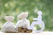 Man on wheelchair and coin money on natural green background,Save money for prepare in future and handicapped person concept