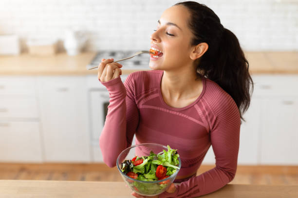 istock Sporty lady eats healthy veggie salad in modern home kitchen 1856848912