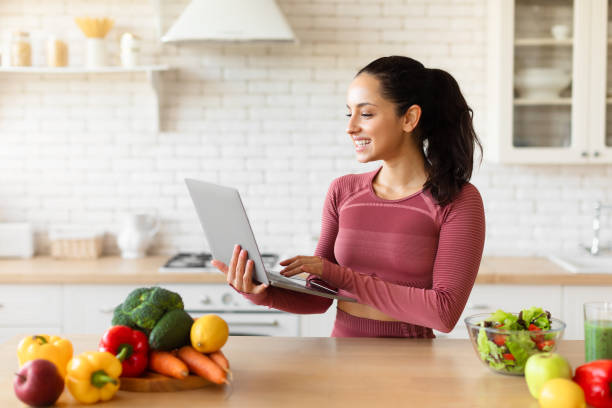 istock Fit lady using laptop browsing recipes for slimming in kitchen 1856848917