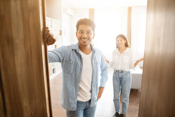 istock Indian couple at door cheerfully inviting people in 1856863059