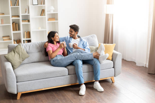 istock Smiling young indian couple drinking coffee and chatting on couch 1856863072