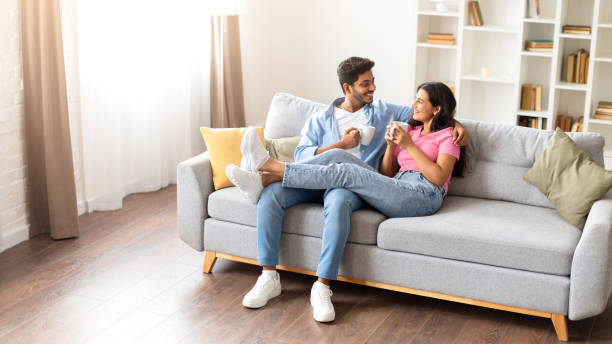 Indian couple talking over coffee on the couch at home