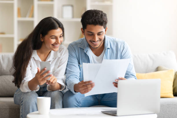 istock Young Indian couple reviewing document, with laptop and coffee 1856863599