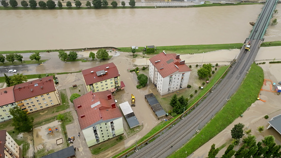 Aerial view of flooded water flowing through river surrounded by houses in village.