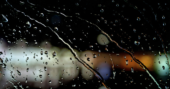 Rain drops on window glass at night with bokeh lights
