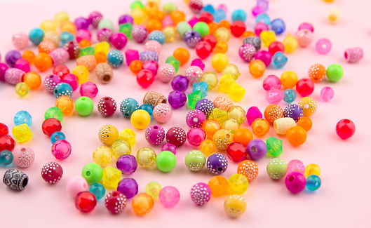Combination of beads and beads on a pink background. Mock up and abstract, colorful background. concept of needlework, creativity and hobbies.