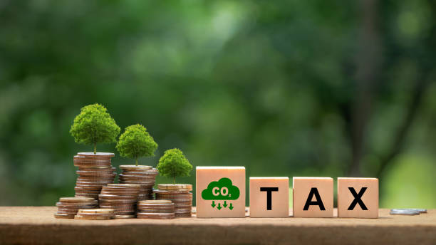 Co2 Tax.Carbon tax, environmental and social responsibility business concept.Controlling carbon emission. Words TAX on a wooden cube with Co2 icon and coin money stack.Taxation for nature pollution. impuesto sobre el co2.concepto de negocio de impuesto al carbono, responsabilidad ambiental y social. control de las emisiones de carbono. palabras tax en un cubo de madera con el icono de co2 y una pila de monedas. tributación por contaminación de la na