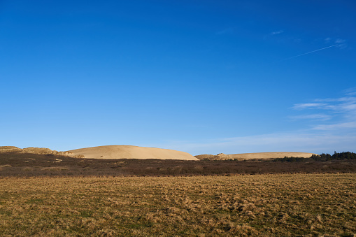 Vast expanses of sand desert and a small figure of a man in the distance. The relief of sand dunes is clearly visible.