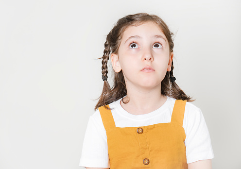 Thoughtful little girl looking away thinking isolated on white background