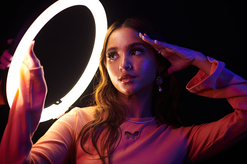 Young woman with nose piercing posing under ring light