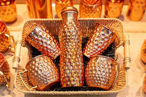Retail display of an array of copper products, including cups and water bottles, for sale at the market.