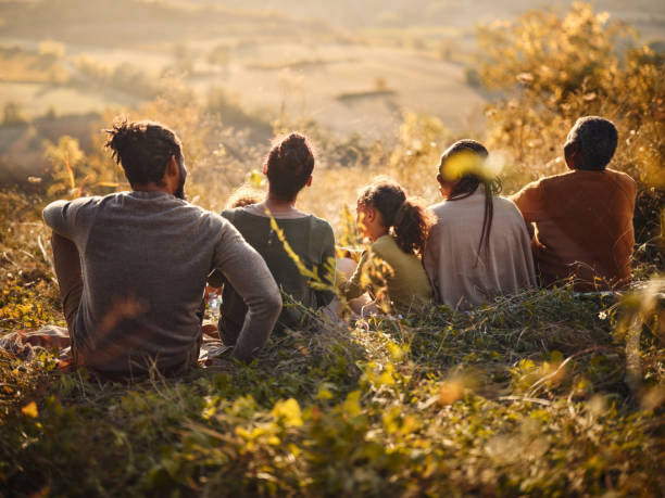 istock Back view of black multi-generation family relaxing in grass on a hill. 1857050810