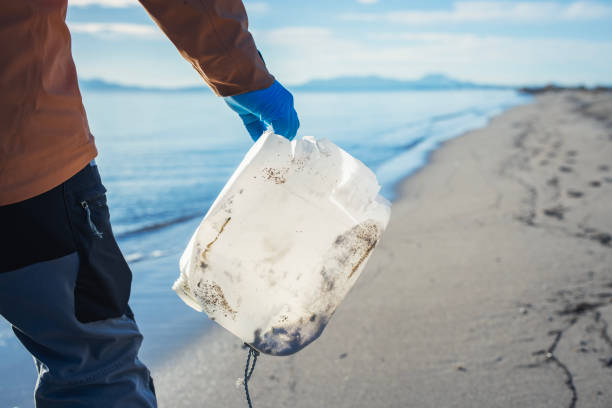 istock Man cleaning up the beach from plastic garbage. 1857056095