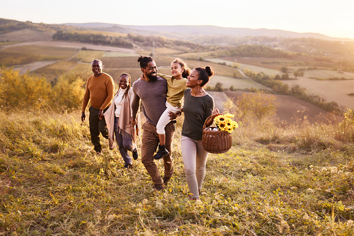 Happy African American extended family enjoying while going on a picnic in autumn day. Copy space.
