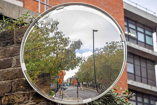 Highgate Hill, London, England - October 31th 2023:  Pullout mirror at a driveway leading out in a steep road over a hill