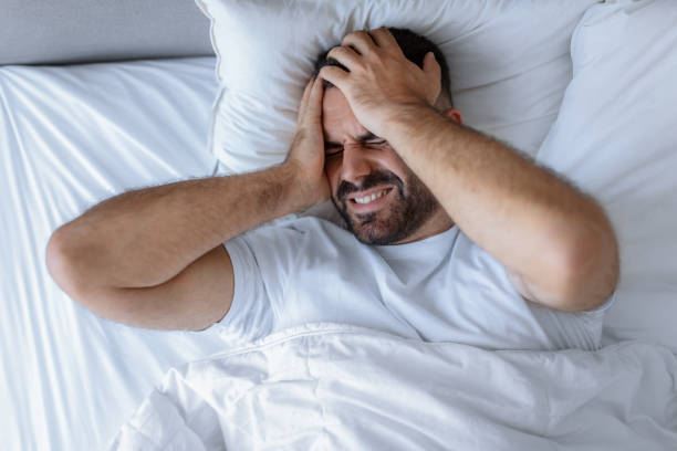 istock Sleepless man lying in bed touching aching head at home 1857087036