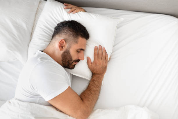 istock man sleeps in bed hugging pillow for comfort in bedroom 1857087044