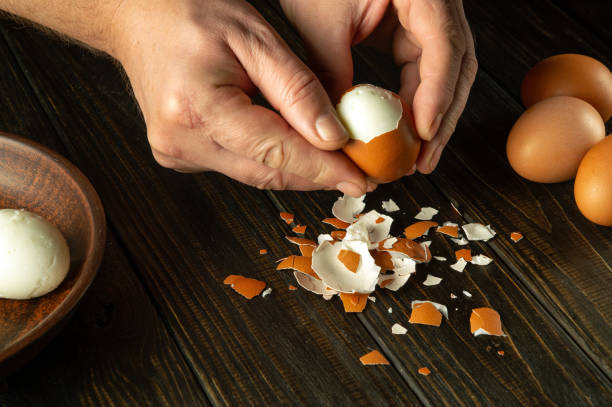 istock Cooking a delicious lunch with boiled eggs on the kitchen table. Shelling an egg with the hands of a chef 1857097412