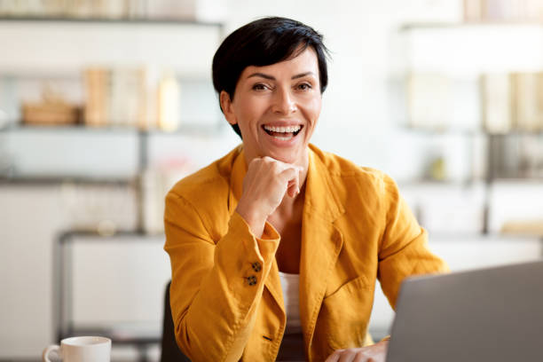 istock Happy business lady posing at work table with laptop indoor 1857115234