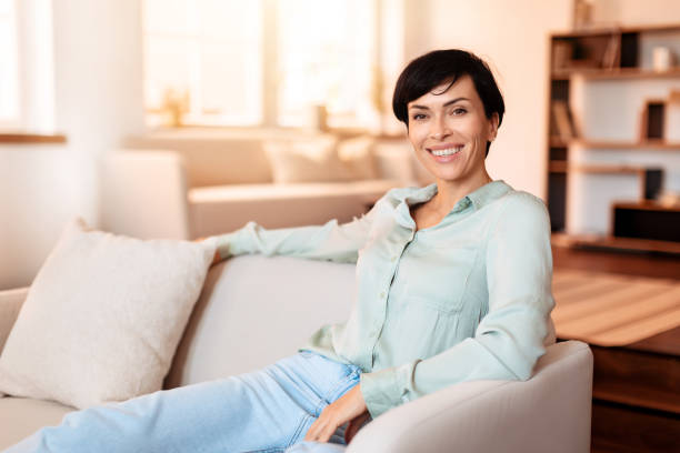 istock Cheerful middle aged lady sitting elegantly on living room sofa 1857117384