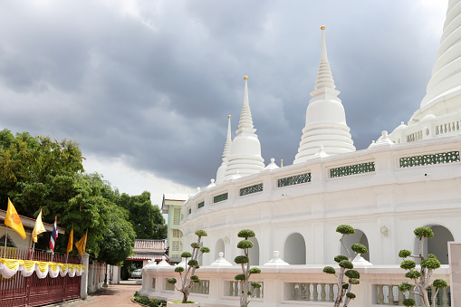 White pagodas in curve row and gray cloudy sky, wat Prayurawongswat Bangkok, Thailand.