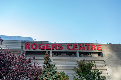 Rogers Centre, home of the Toronto Blue Jays, at the base of the CN Tower in Toronto, Ontario, Canada on a bright Autumn day with a cloudless sky.