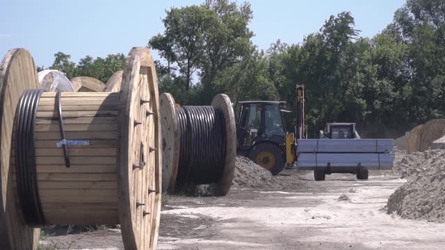 Construction site footage, spools of cable, heavy machinery at work, industrial