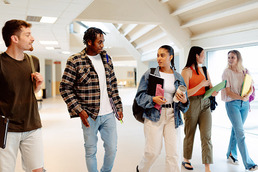 mutiracial group of girls and boys walking together in the halls of the university or high school. Students from different cultures together at school