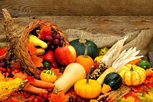Harvest or Thanksgiving cornucopia filled with vegetables against wood background