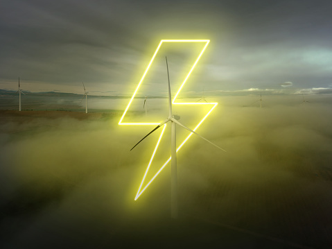 A glowing yellow neon light with ray shape over wind turbines