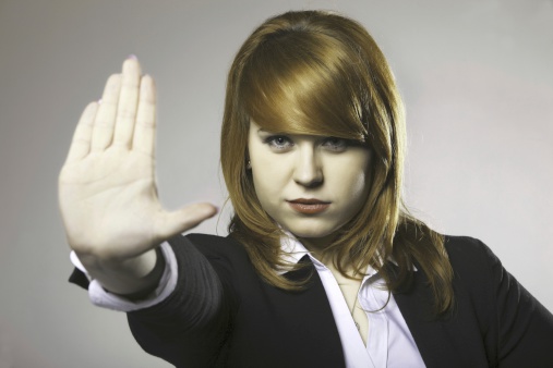 Young business woman making stop gesture sign on gray background