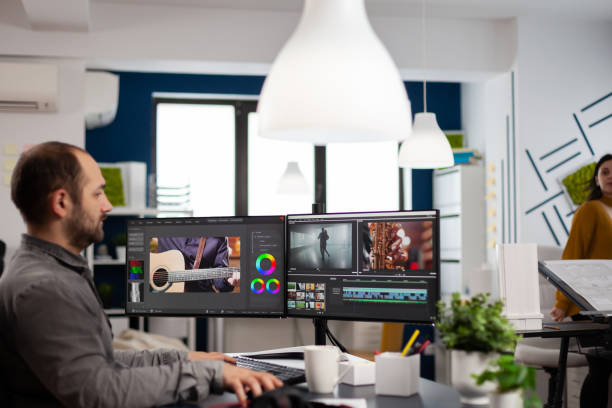 istock Videographer editing, cuting footage and sound on computer with dual monitors 1857179846