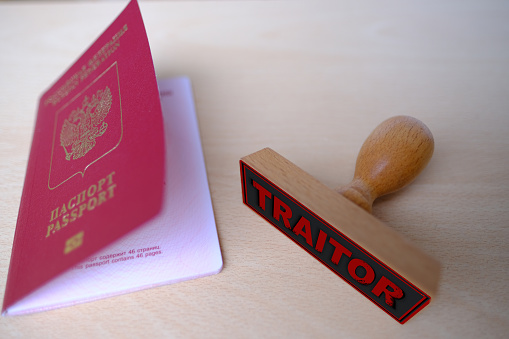 foreign, International biometric Russian passports of citizen of Russian Federation with red cover close up on light background, stamp of traitor. Stop illegal migration concept accusation of treason