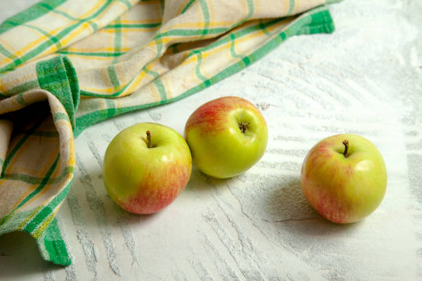 istock Three green apples on white wooden background. 1857189217
