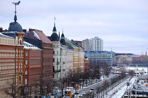 flow of cars, passenger buses rides along Pohjoisranta street, winter street Helsinki city, yachts and ships stand in northern port, concept passenger traffic, Helsinki, Finland - January 1, 2022