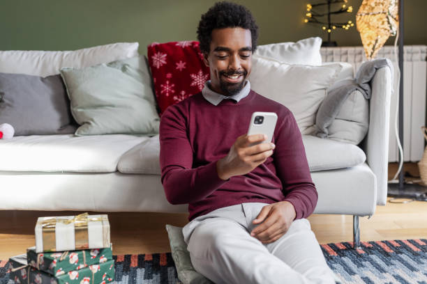 istock Young African American man using phone at home, during Holidays 1857198718