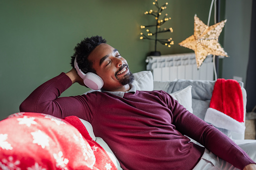 Young African American man relaxing on the sofa during Christmas Holidays