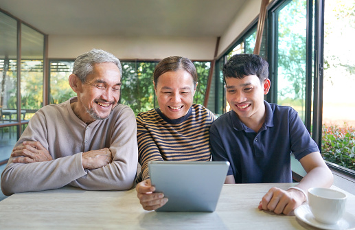 happy asian family,senior adult father and mother with young adult son enjoy using using tablet internet online in cafa