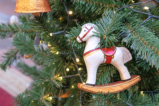 Vintage Christmas tree toy rocking horse made of papier-mache on Christmas tree with a garland.
