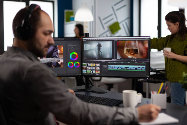 istock Video maker with headset working with footage and sound on pc with two displays 1857230453