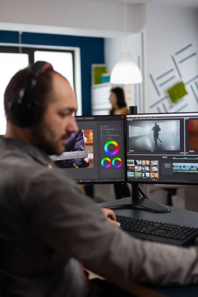 istock Video maker with headset working with footage and sound on pc with two displays 1857230467