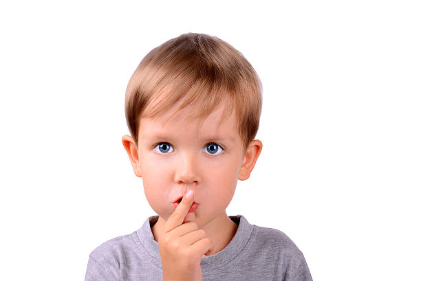 istock boy covers up his mouth with finger closeup 185724478