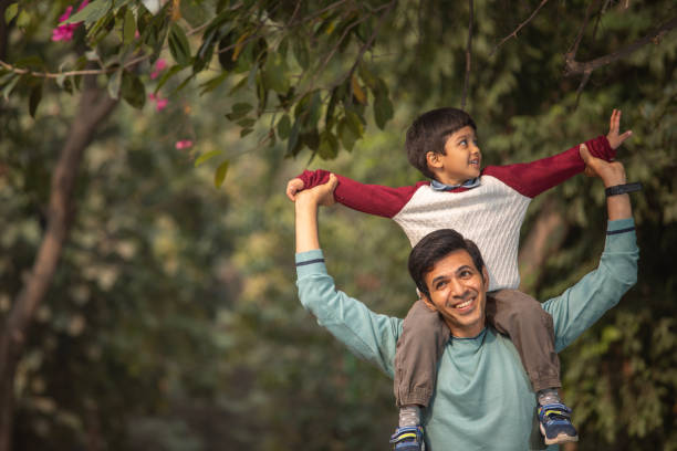 istock Happy son sitting on father shoulders in garden 1857246282