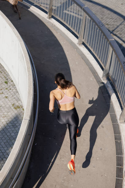istock High angle view on active woman running on the curved elevated walkway with her dog 1857272930