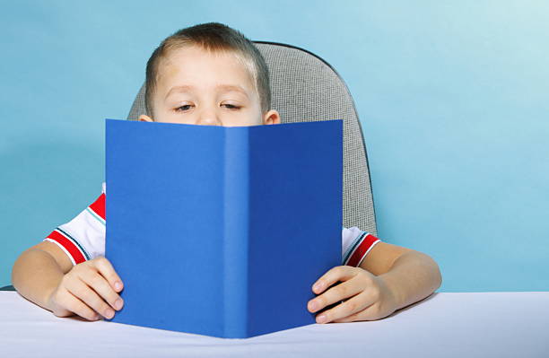 istock child boy kid reading a book on blue 185729783