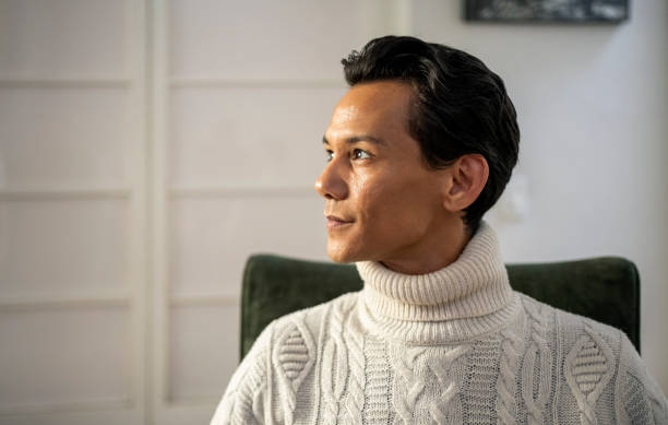 istock Confident young man in white sweater looking away at home 1857326852
